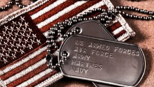 Dog tags with "US ARMED FORCES AIR FORCE ARMY MARINES NAVY" inscription lie on a USA flag patch.