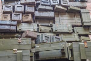 A large stack of weathered wooden crates and boxes arranged unevenly, some with metal latches and visible signs of age.